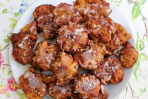 Golden-brown sourdough apple fritters with a light vanilla glaze on a white plate, perfect for a fall treat.