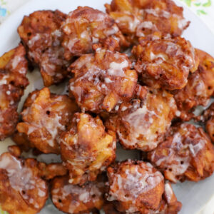 Close-up of golden-brown sourdough apple fritters drizzled with vanilla glaze, showcasing the crisp texture and apple chunks.