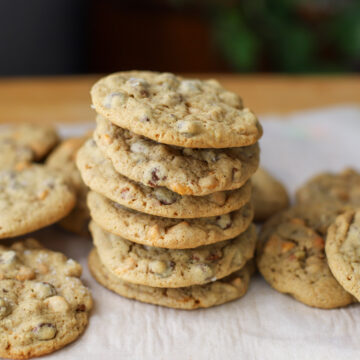 Stack of sourdough chocolate chip cookies with butterscotch chips and toasted pecans, arranged on parchment paper for a delightful dessert.