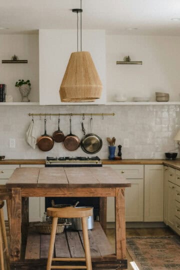 A beautifully designed rustic kitchen with warm wood tones, hanging copper pots, and an inviting island, perfect for passionate home cooks and bakers.