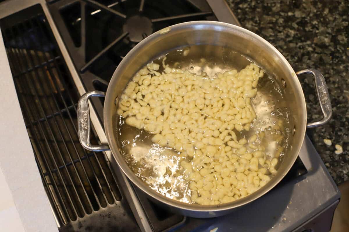 Spaetzle dumplings floating in a pot of simmering water on the stovetop