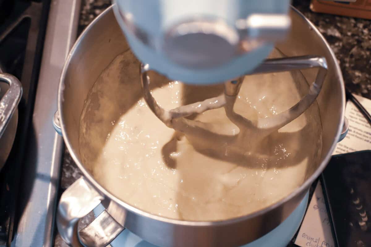 Thick spaetzle batter being mixed with the paddle attachment in a stainless steel stand mixer bowl