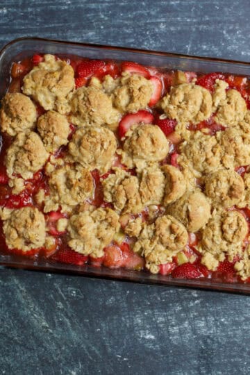 Baked strawberry rhubarb crumble with a golden oat crumble topping in a glass baking dish