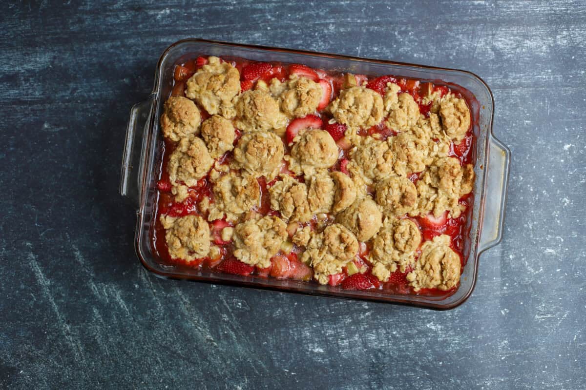 Baked strawberry rhubarb crumble with a golden oat crumble topping in a glass baking dish