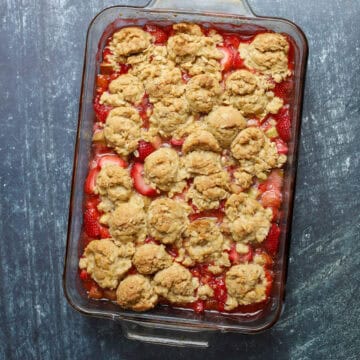Overhead view of strawberry rhubarb crumble with golden oat topping in a rectangular glass baking dish